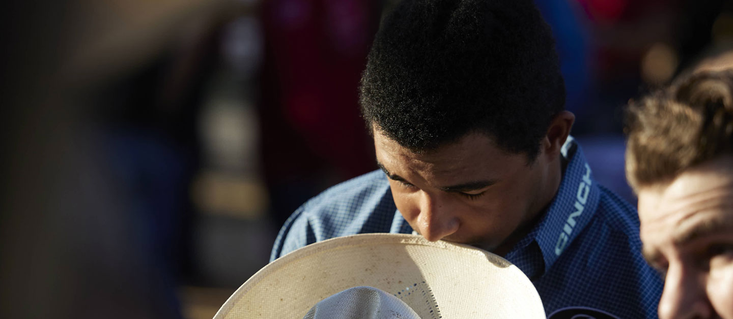 Laramie Mosley praying before the rodeo with his hat off.